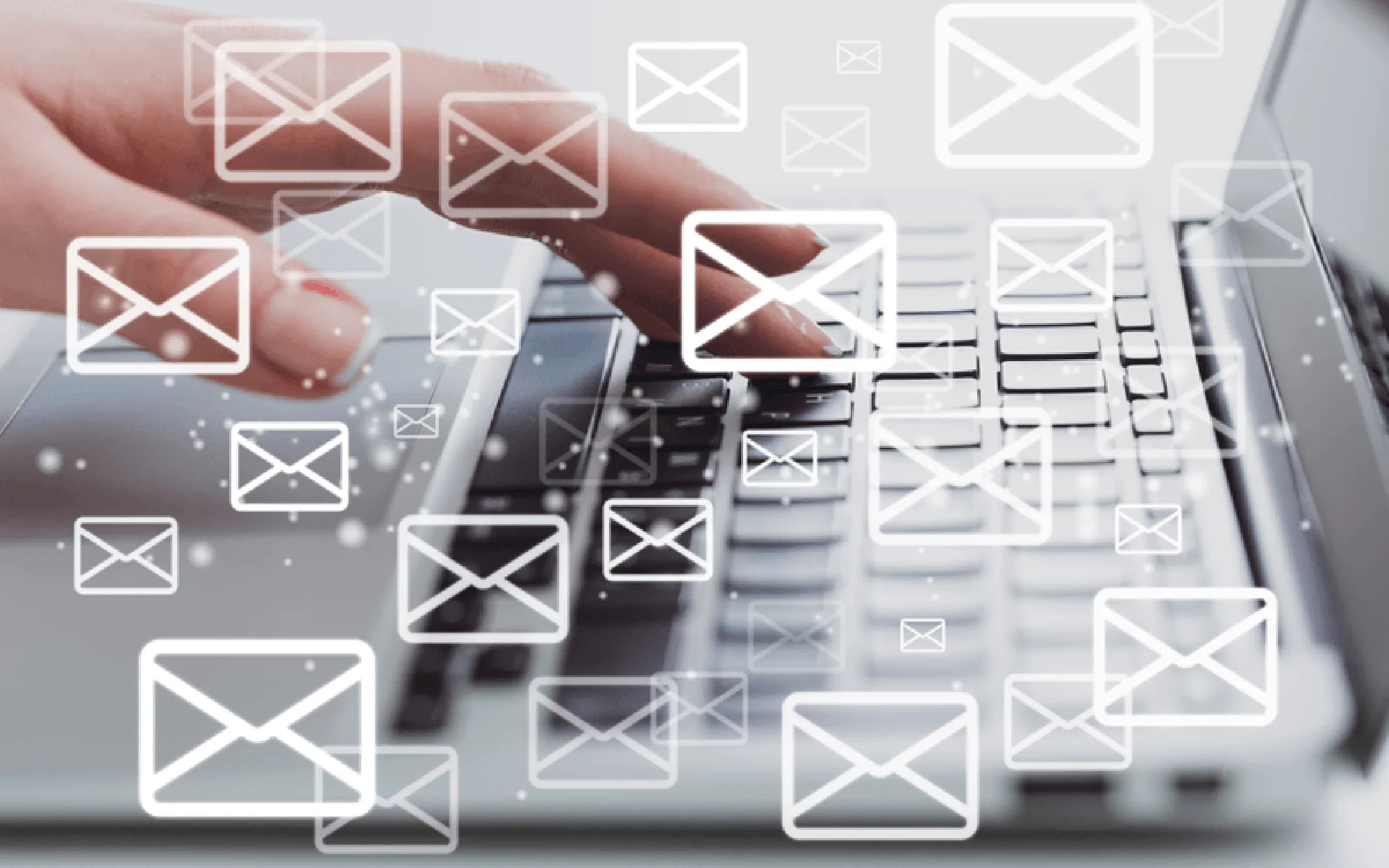 Eine Hand tippt auf einer Laptop-Tastatur, während mehrere schwebende E-Mail-Symbole im Vordergrund dargestellt sind.