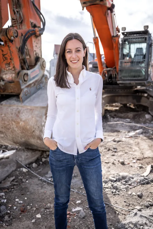 Frau Eberhart von der Verticali GmbH & Co. KG auf einer Baustelle vor einem Bagger.